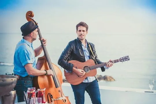 Stelios Antoniou playing guitar in a seaside duo with a double bass player
