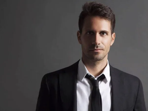 Studio portrait of Stelios Antoniou in a black suit and tie